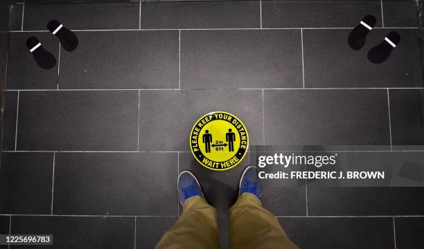Foot markings and a coronavirus social distance reminder are seen on the floor of an elevator in office building in Hollywood, California on July 7,...