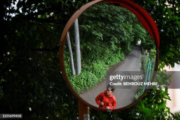 This photo taken on June 18, 2020 shows Japanese boxer and nurse Arisa Tsubata reflected in a convex mirror as she runs near her apartment in...