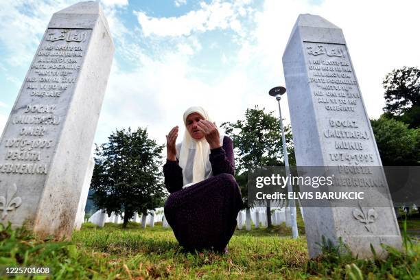 Bosnian Muslim woman Mejra Djogaz survivor of Srebrenica 1995 massacre, prays between her sons' tombstones, Omer and Munib her two sons killed in the...