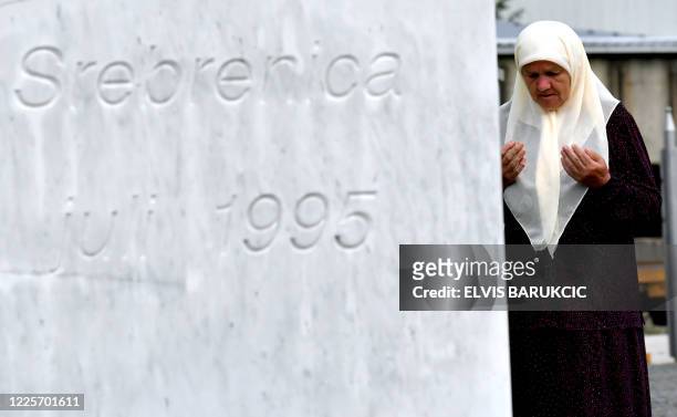 Bosnian Muslim woman Mejra Djogaz survivor of Srebrenica 1995 massacre, prays at the entrance of the Potocari memorial center near Srebrenica, where...