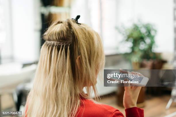 middle-aged woman in a beauty salon talking with mobile phone - alongamento de cabelo - fotografias e filmes do acervo