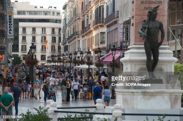 General view of people wearing face masks walking along the Marques de Larios street. Spaniards continue living daily life under the new normality...