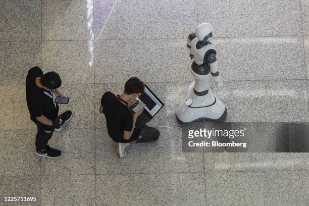 Technicians run diagnostics to a humanoid robot in the exhibition display area at the World AI Conference in Shanghai, China, on Thursday, July 9,...