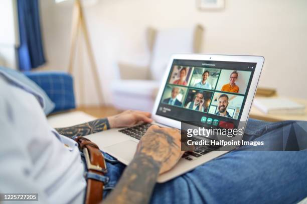 unrecognizable young businessman with laptop working indoors in home office, having online meeting. - op schoot stockfoto's en -beelden