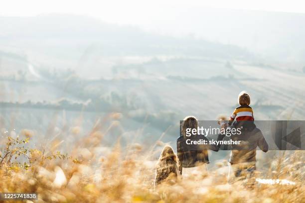 rear view of a family standing on a hill in autumn day. - sunday stock pictures, royalty-free photos & images
