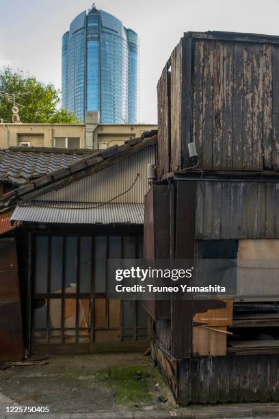 the abandoned house and the high-rise building behind it - 廃墟　日本 ストックフォトと画像