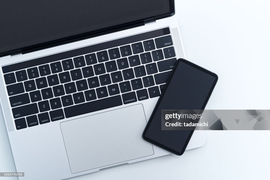 Smartphone and laptop computer on white background from above.
