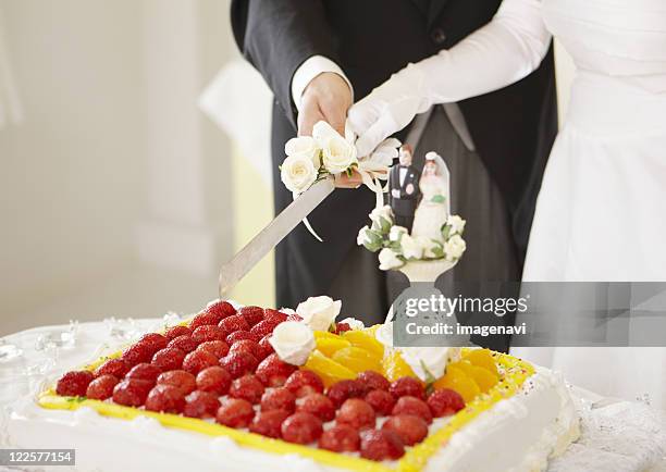 bride and groom cutting wedding cake - wedding cake figurine photos et images de collection