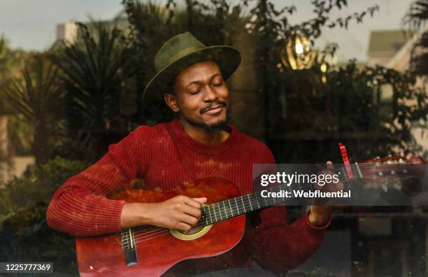 influencer from south africa playing the guitar while self-isolating - plucking an instrument fotografías e imágenes de stock