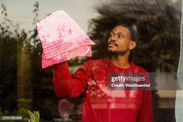 south african man cleaning a window while self-isolation - webfluential - fotografias e filmes do acervo