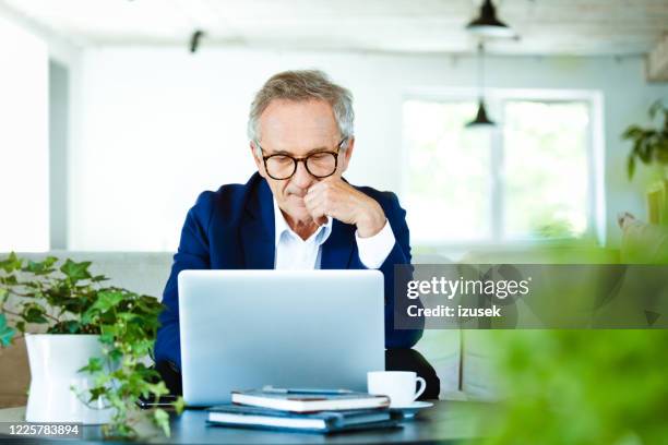 worried senior businessman working on laptop at home - retirement decisions stock pictures, royalty-free photos & images