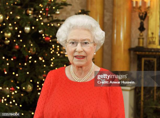 Queen Elizabeth II stands in front of a Christmas tree at Buckingham Palace after recording her Christmas Day television broadcast to the...