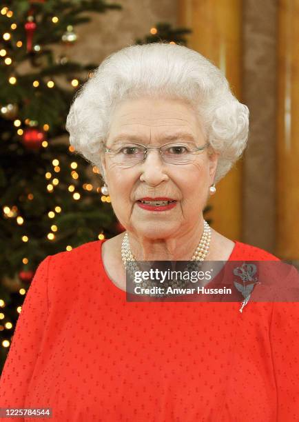 Queen Elizabeth II stands in front of a Christmas tree at Buckingham Palace after recording her Christmas Day television broadcast to the...