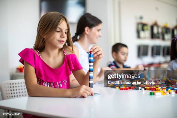 cute little girl having fun with plastic blocks at day care playroom - public school building stock pictures, royalty-free photos & images