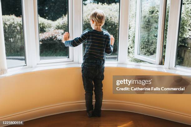 boy looking out a window - 不穏状態 ストックフォトと画像