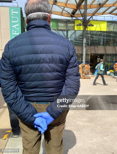 Homme portant des gants faisant la queue devant la jardinerie "Truffaut" lors du déconfinement suite à l'épidémie de Coranavirus Covid-19, le 12 mai...