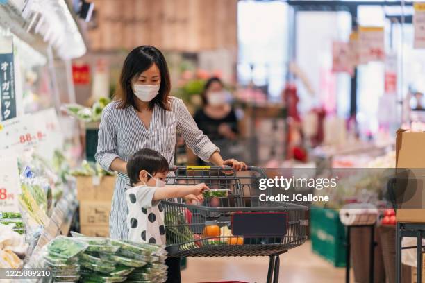 mother and son wearing face masks shopping together in a supermarket - supermarket covid stock pictures, royalty-free photos & images