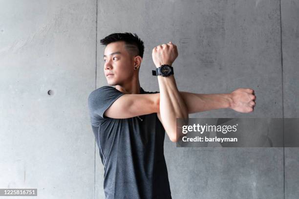 a young chinese man stretching body in a urban architecture - asian man exercise stock pictures, royalty-free photos & images