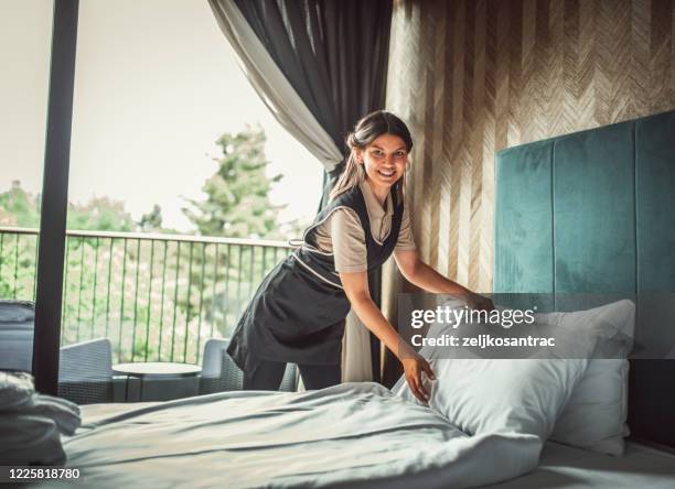 huishoudster die het bed in een hotel maakt - house cleaning stockfoto's en -beelden