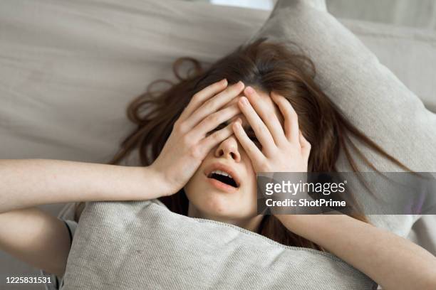 the woman lies in bed and woke up with a terrible headache and poor health. - hangover stockfoto's en -beelden