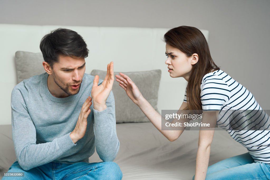 A young couple of man and woman swear at home.