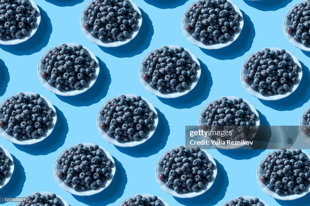 Blueberries on the plate on the blue background