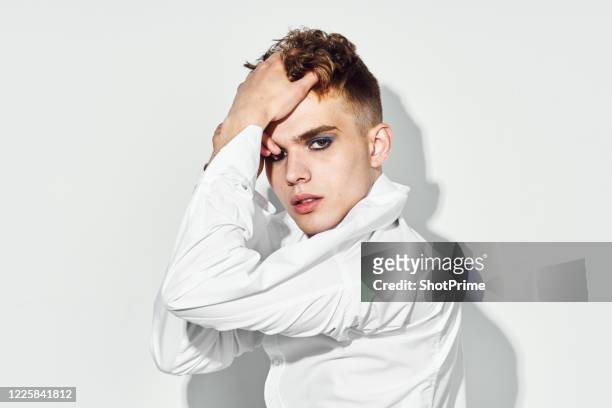 fashion photo of a young guy with makeup on his eyes. - androgynous - fotografias e filmes do acervo