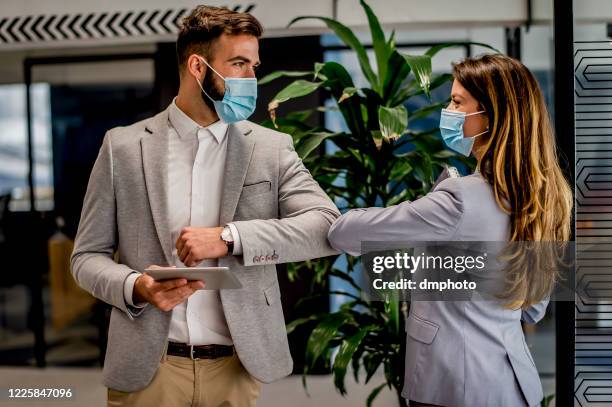 business people greeting during covid-19 pandemic, elbow bump - protective face mask office stock pictures, royalty-free photos & images