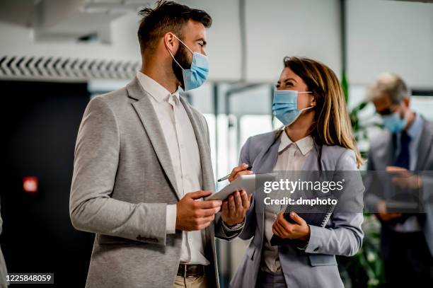 businessman and businesswoman having a meeting wearing face masks - business meeting covid stock pictures, royalty-free photos & images