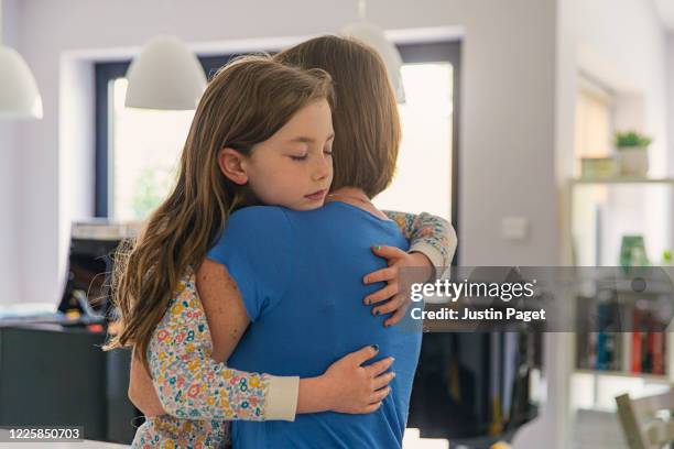 young girl getting a big cuddle from her mum - child mental health wellness foto e immagini stock