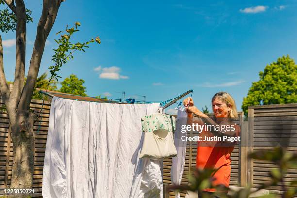 senior woman hanging up her washing - laundry woman stock pictures, royalty-free photos & images