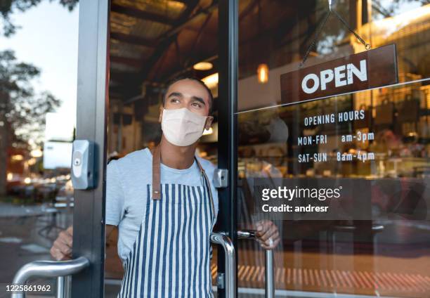 business owner opening the door at a cafe wearing a facemask - opening event stock pictures, royalty-free photos & images