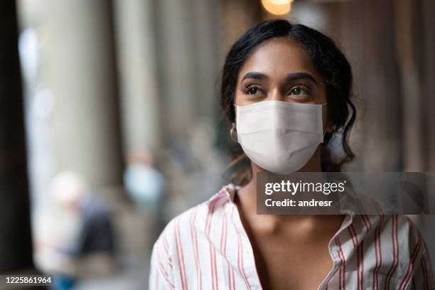 thoughtful mixed-race woman on the street wearing a facemask - pollution mask stock pictures, royalty-free photos & images