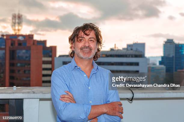 a relaxed and happy latin american boss on the terrace of his office building partying with his staff at sunset time - tousled hair man stock pictures, royalty-free photos & images