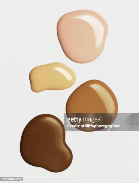 overhead close-up view of four liquid foundation texture in a group from light to dark, isolated on white background - smudged stock pictures, royalty-free photos & images