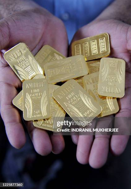 Worker displays gold bars at the National Indian Bullion Refinery 's gold and silver refinery in Mumbai on November 6, 2009. The price of gold surged...