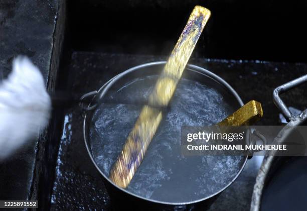 Worker immerses hot gold bars into liquid at the National Indian Bullion Refinery 's gold and silver refinery in Mumbai on November 6, 2009. The...