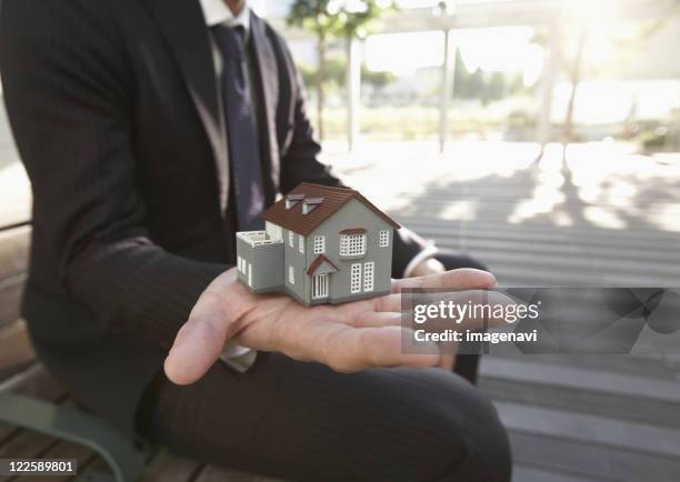 Businessmans Hand Holding Miniature House, Foto de stock