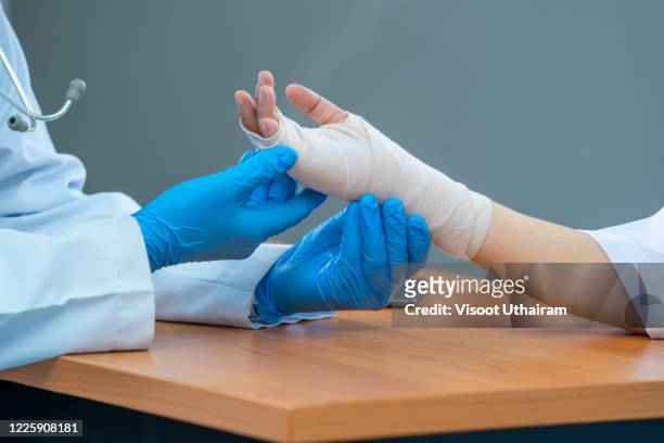 doctor examining hand of patient while the patient has pain at clinic. - bandage stockfoto's en -beelden