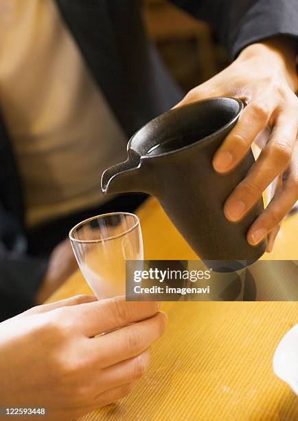 man pouring japanese sake - copo de saké - fotografias e filmes do acervo