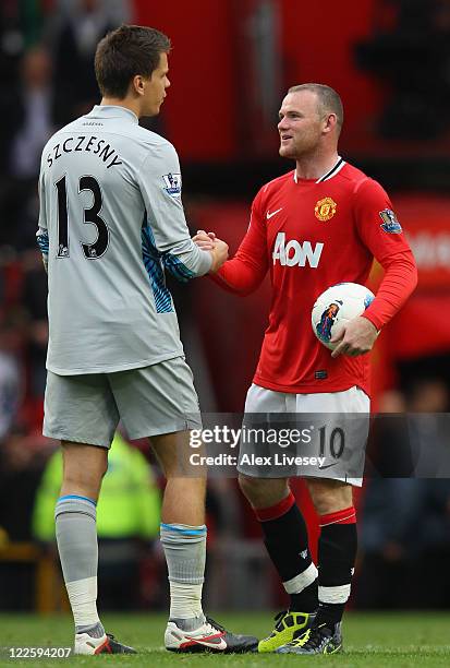 Wayne Rooney of Manchester United carries the match ball as he shakes hands with Wojciech Szczesny of Arsenal after the Barclays Premier League match...