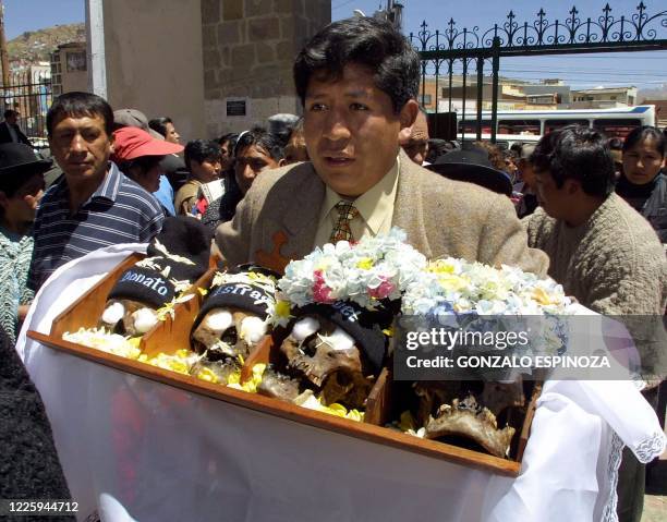 Man carries four human skulls to be blessed in a cemetery in La Paz, Bolivia , 08 November 2002, on the day of the "Ñatitas". This annual tradition...