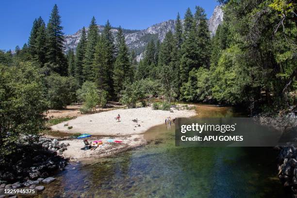 Visitors sunbathe at Merced River in Yosemite National Park, California on July 04, 2020. - After closing for 2½ months because of the coronavirus...