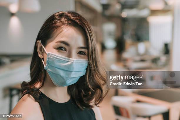 an asian chinese beautiful woman looking at camera smiling with her face mask surgical mask on - businesswoman mask stock pictures, royalty-free photos & images