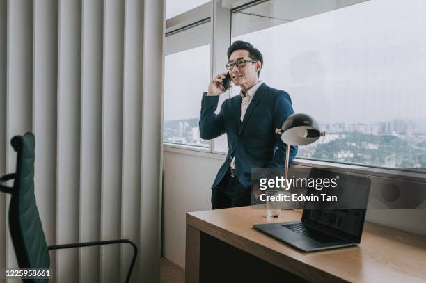 an asian chinese mid adult handsome white collar worker working in the office listening to his phone - wealthy asian man stock pictures, royalty-free photos & images