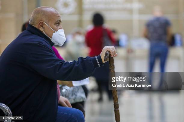 Senior citizen wearing a protective facemask and keep a social distance from each other while queuing inside ASAN service in Baku on May 20, 2020 in...