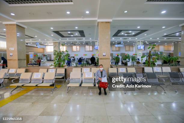 Senior citizens wearing a protective facemask and keep a social distance from each other while queuing inside ASAN service in Baku on May 20, 2020 in...