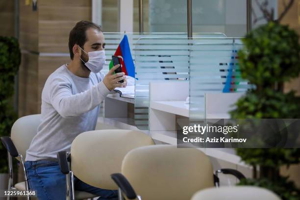 Young man wearing a protective facemask and show online document inside ASAN service in Baku on May 20, 2020 in Baku, Azerbaijan. The coronavirus...