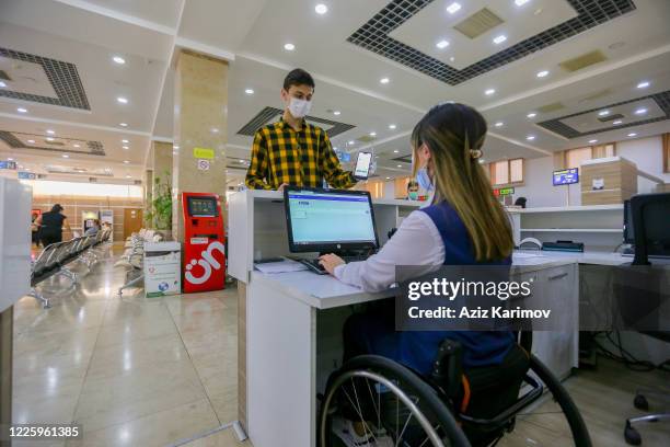 Young man wearing a protective facemask and show online document inside ASAN service in Baku on May 20, 2020 in Baku, Azerbaijan. The coronavirus...