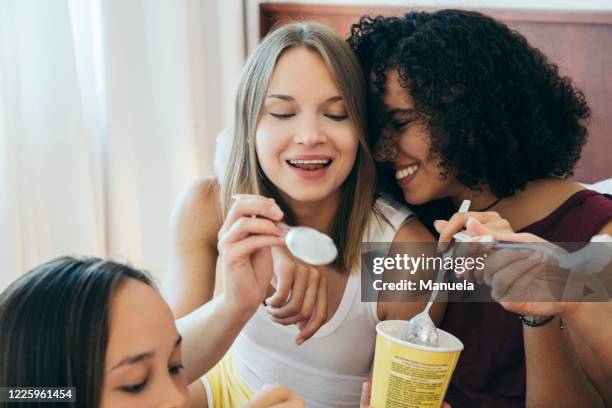 three women eating from tubs of ice cream and laughing. - ice cream cup stock-fotos und bilder
